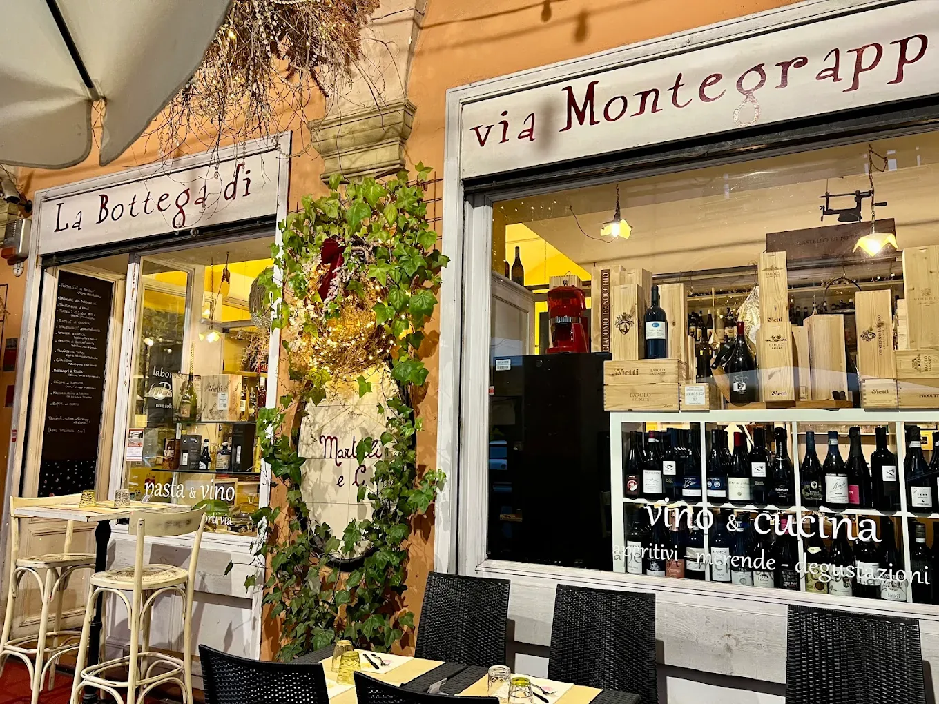 Le vetrine dipinte a mano de La Bottega di Via Montegrappa sotto il portico, piene di bottiglie